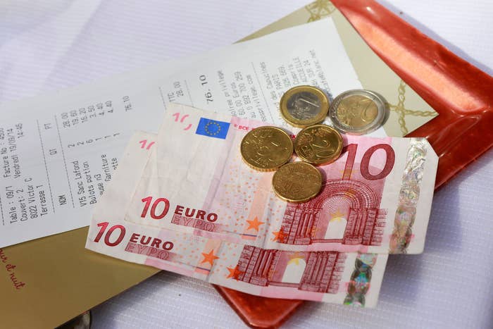 Euro banknotes and coins placed on a restaurant bill and a red tray