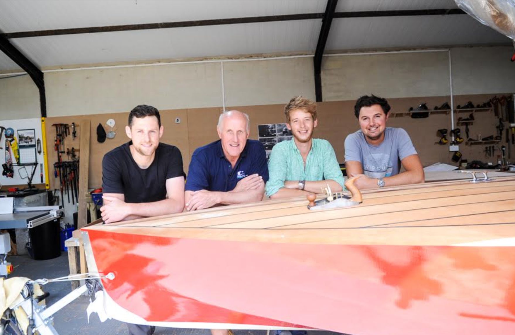 Simon (second from left) in his workshop in 2018 with a boat he built and his (slightly) younger colleagues, Shep (far left), Jamie (second from right) and Sam