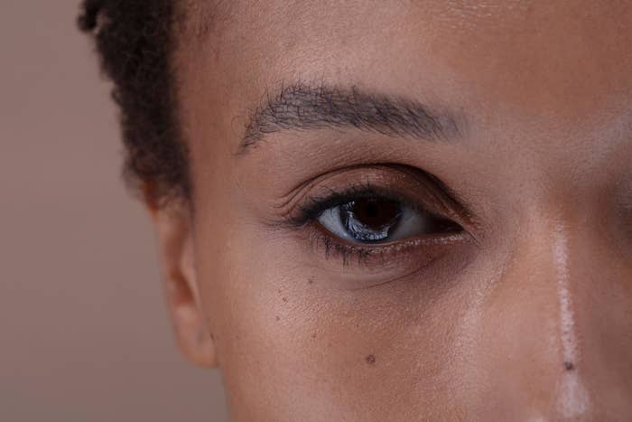 Close-up of a person's eye, showcasing eyelashes, eyebrow, and skin texture