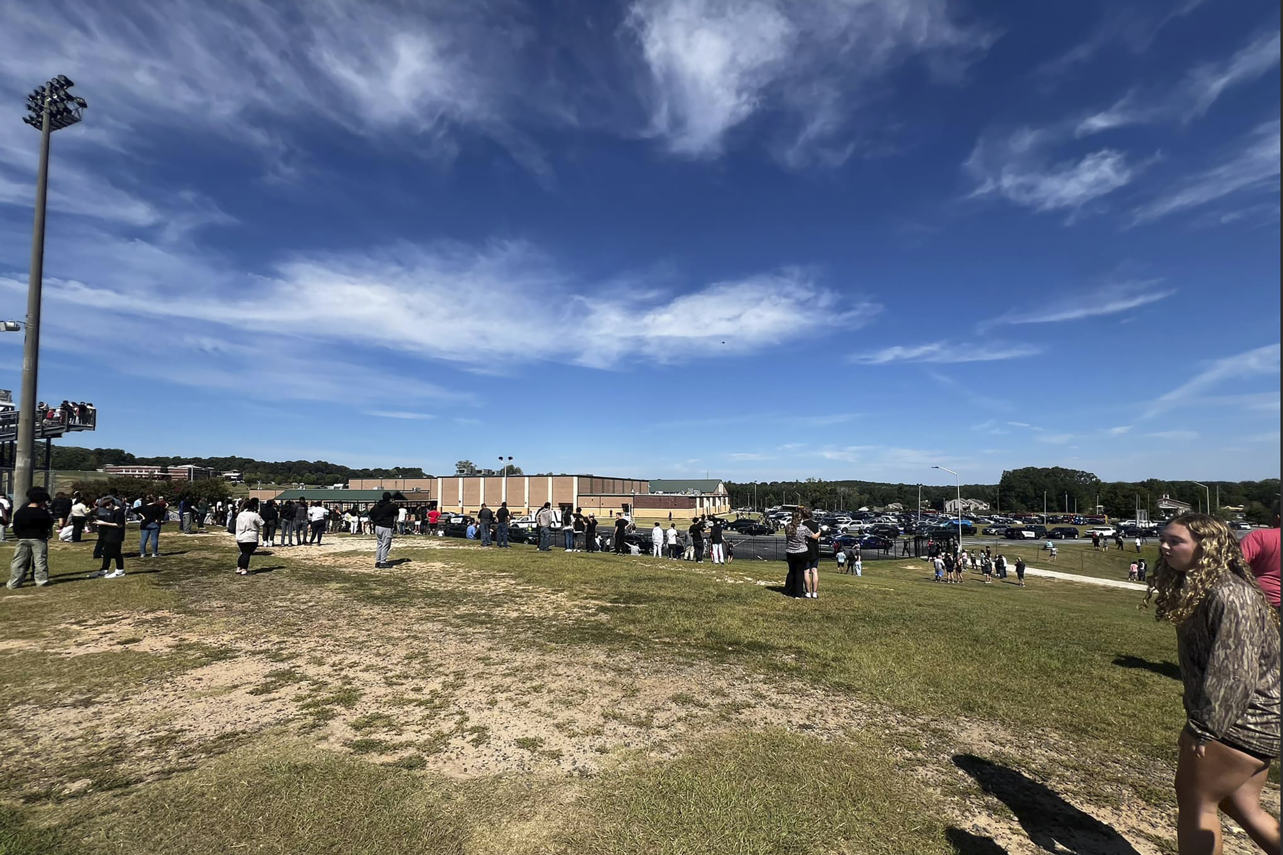 People gathered outside a large building under a clear sky, participating in an outdoor event or activity