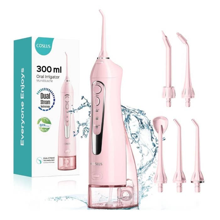 Pink cordless h2o  flosser with 4  interchangeable tips, shown adjacent  to its packaging featuring “300 ml Oral Irrigator” and BPA-free label