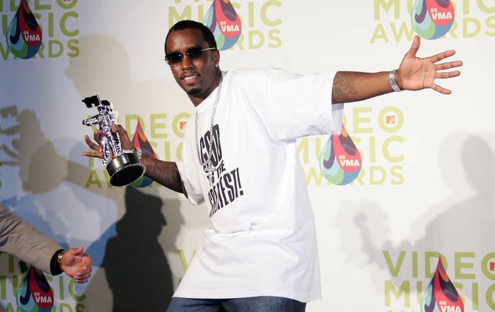 Person in casual t-shirt and jeans holding a VMA trophy, posing playfully on stage at a video music awards event