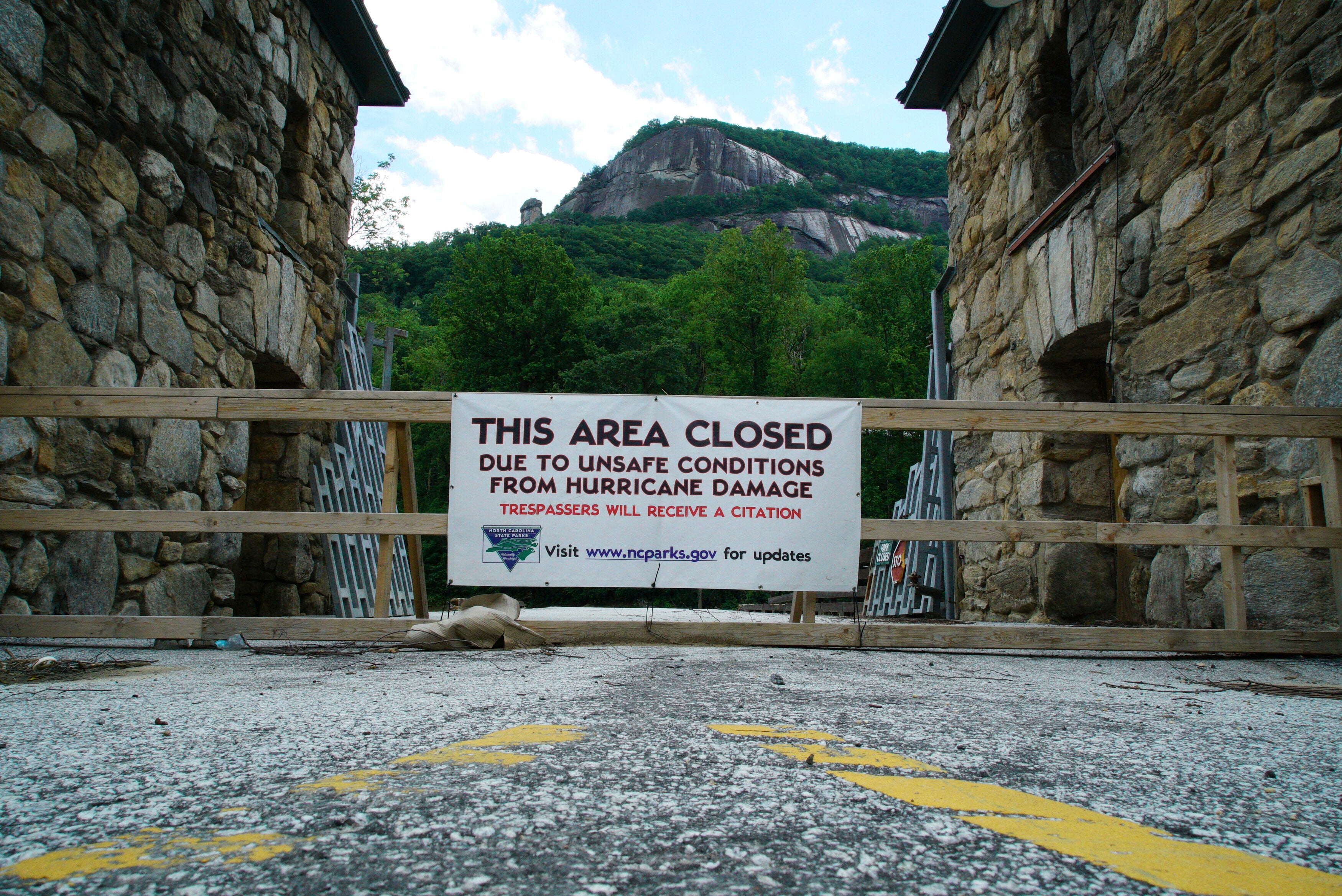 Sign: &quot;This area closed due to unsafe conditions from hurricane damage. Trespassers will receive a citation.&quot; Mountains and sky visible
