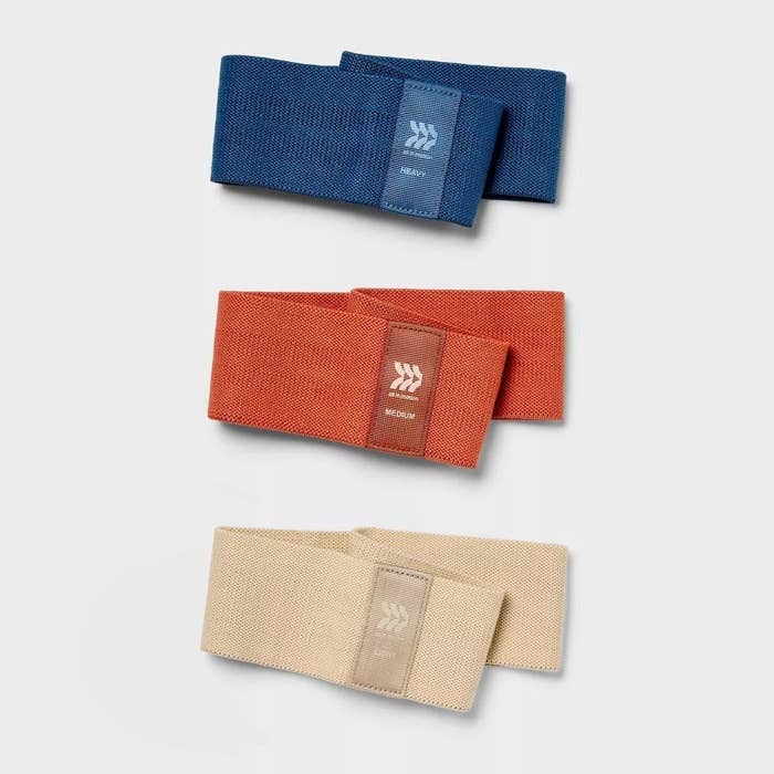 Three resistance bands in blue, orange, and beige are stacked vertically