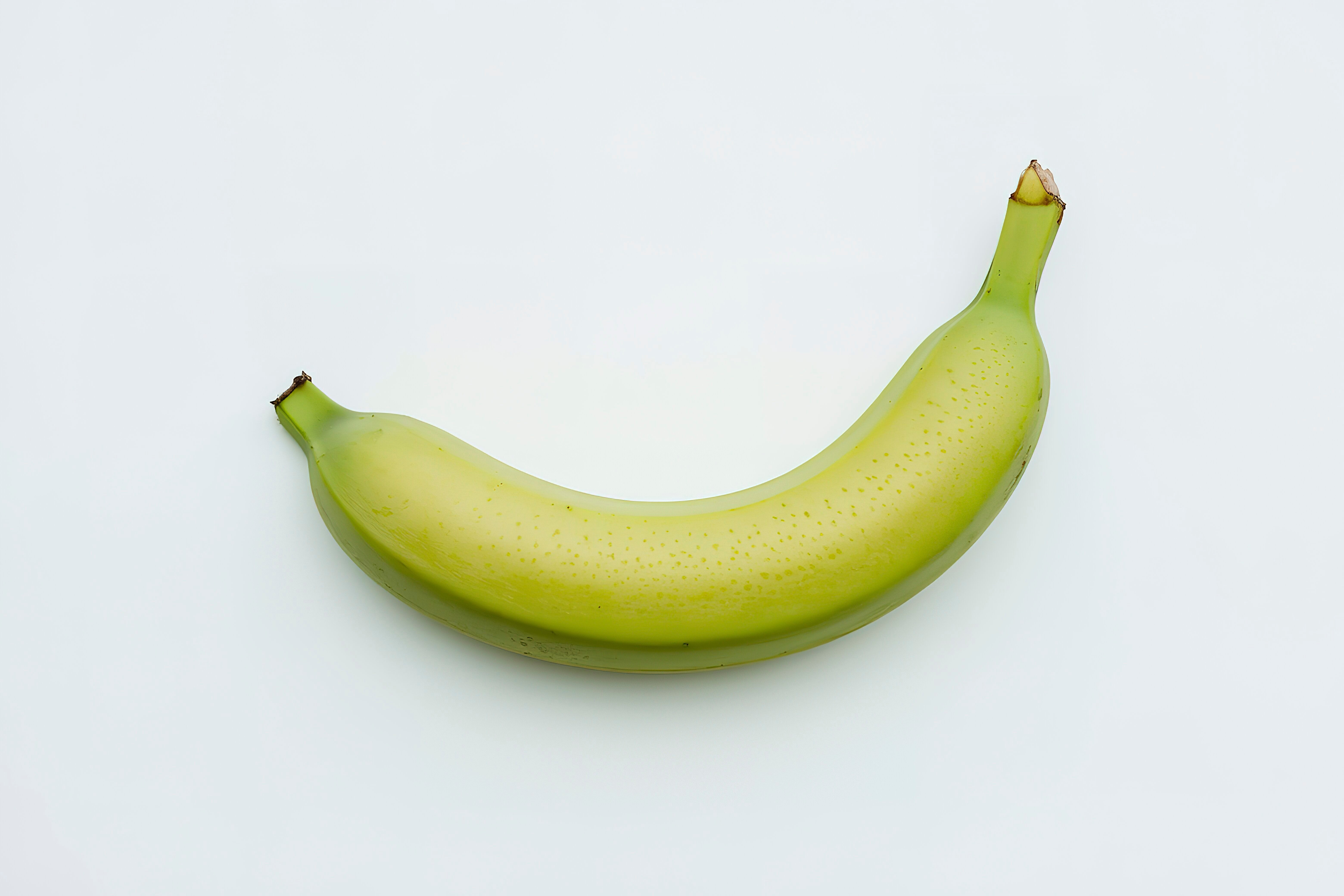 A single ripe banana on a plain background, with one end slightly peeled back