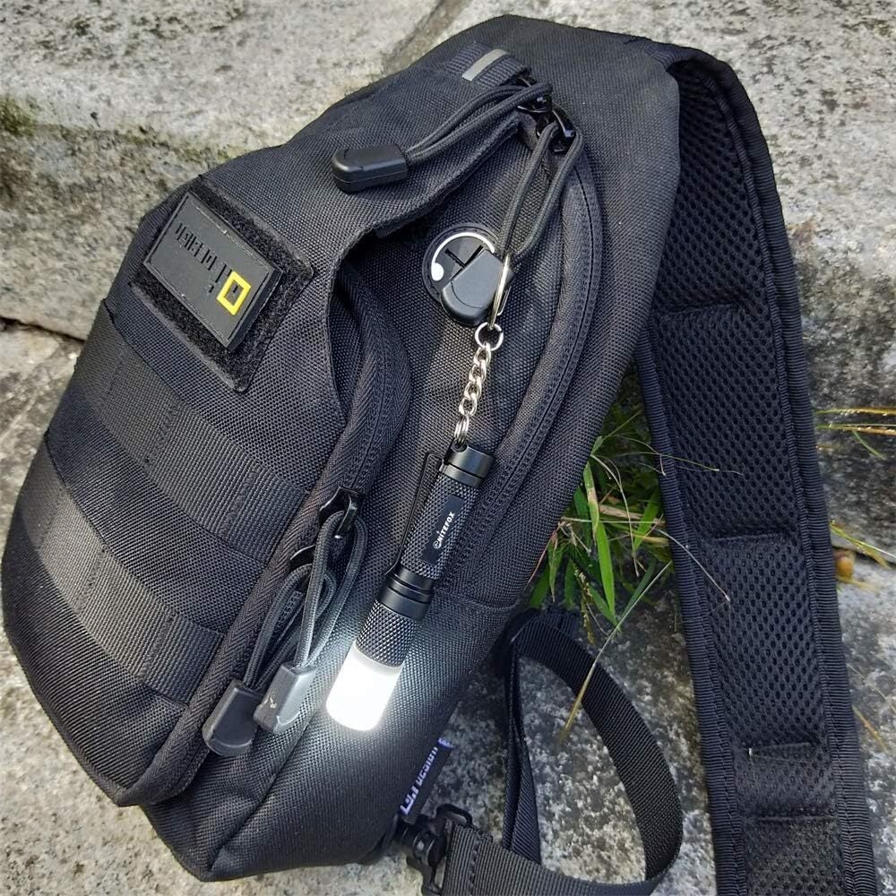 Compact tactical sling container  with aggregate  compartments, featuring a flashlight and keychain attached. Ideal for municipality  and outdoor use