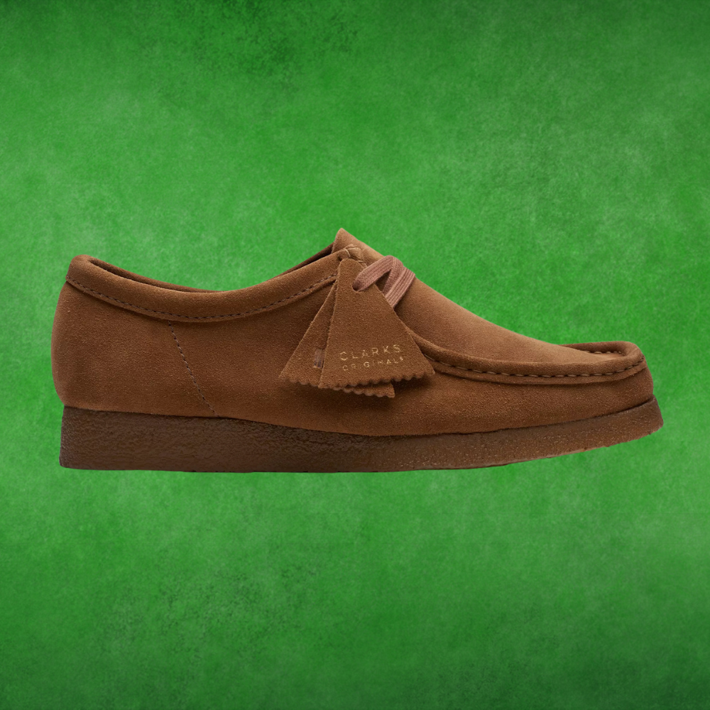 Brown suede moccasin-style footwear  with tag, displayed against a textured background