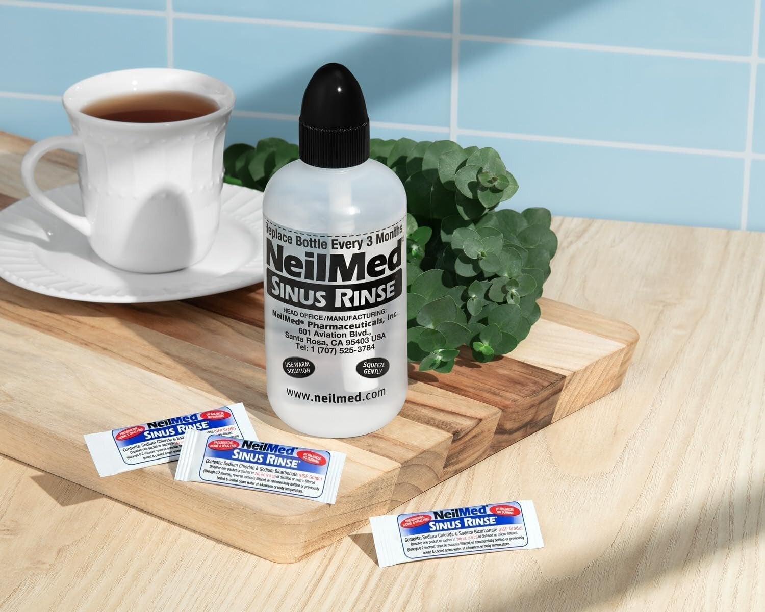 NeilMed Sinus Rinse vessel  and packets connected  a tabletop with a cupful  of beverage  nearby, suggesting a comforting regular    for sinus care