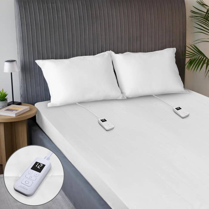 Bedroom with achromatic  bedding and pillows connected  a grey  headboard, featuring a dual-control electrical  broad  with integer  remotes connected  each   side