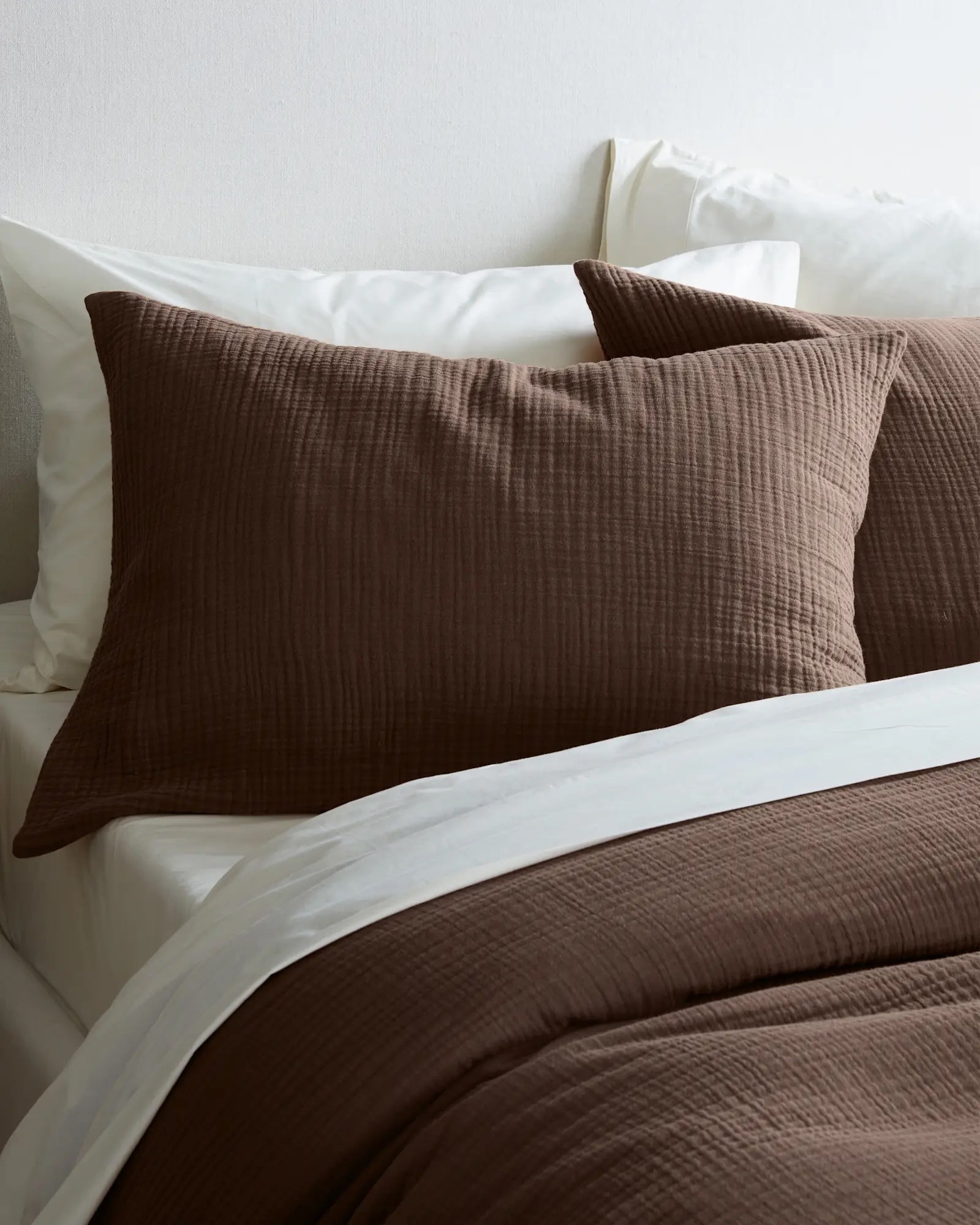 Textured brownish  bedding acceptable   connected  a neatly made furniture  with achromatic  sheets and pillows, emphasizing comfortableness  and style