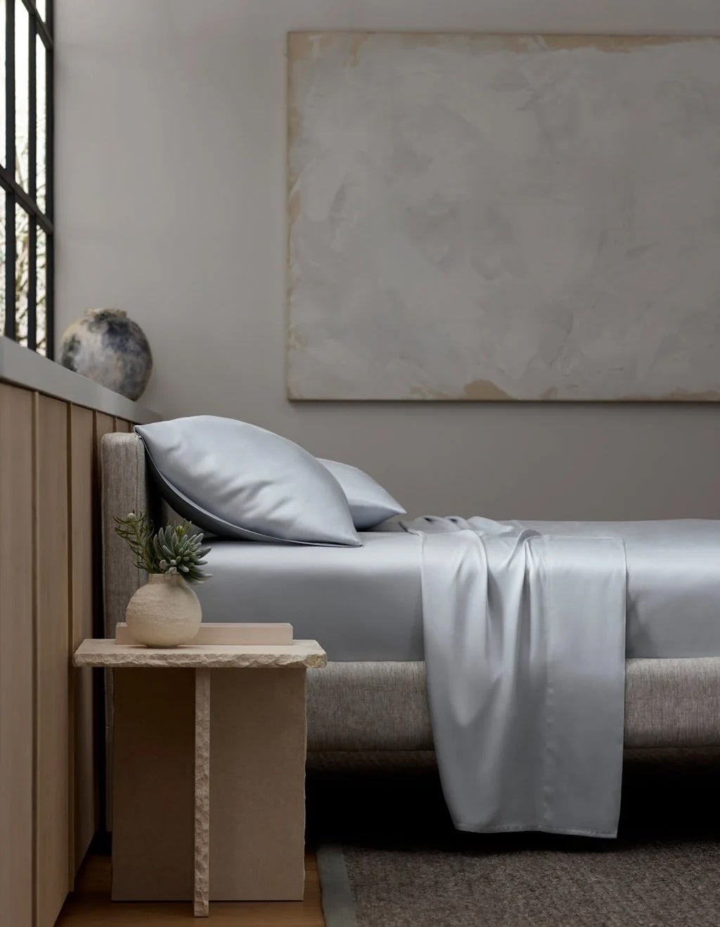 Minimalist chamber  with neatly made furniture  and creaseless  bedding. A tiny  bedside array  holds a succulent and a decorative vase
