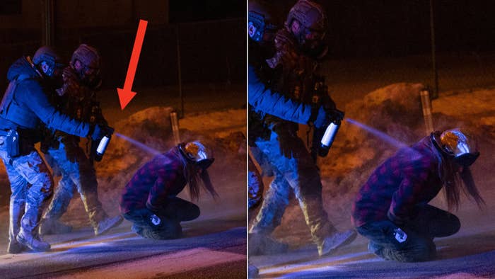 Police officers spray substance on kneeling protester wearing a checkered shirt and protective gear. A red arrow points to the spray can