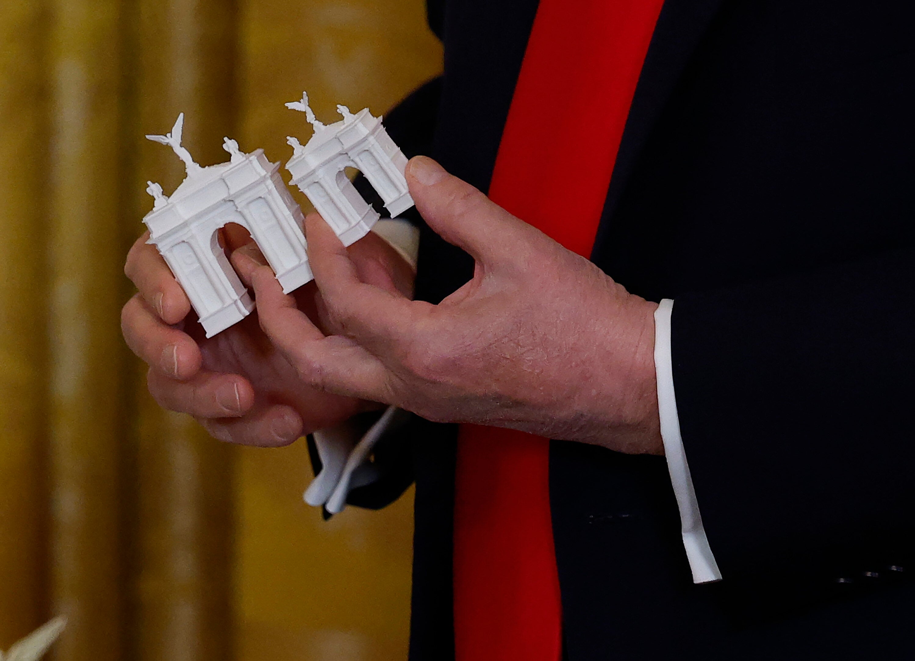 Person holding miniature models of classical arches