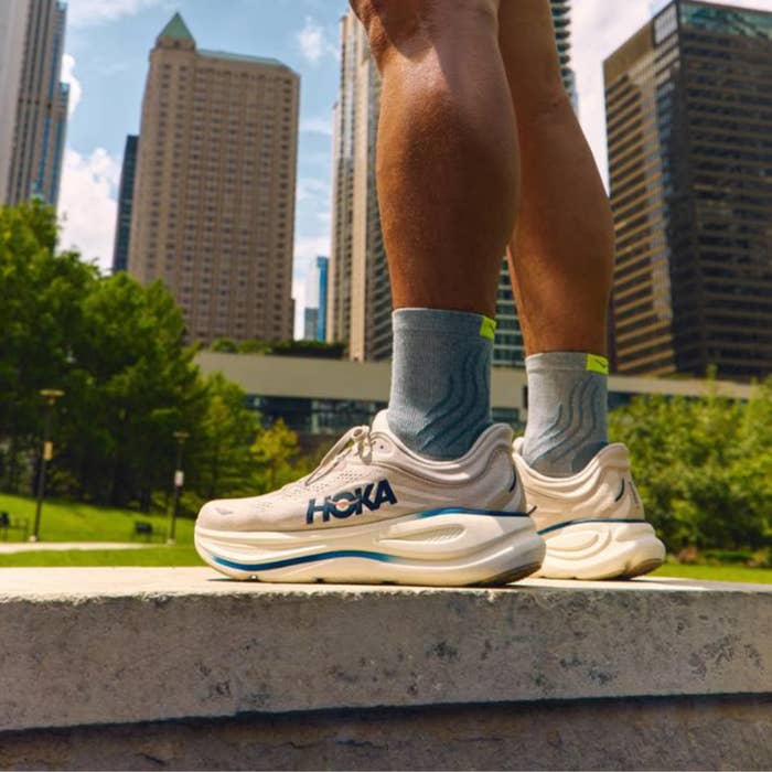 Person wearing diversion  sneakers and socks, lasting  connected  a factual  ledge with skyscrapers and a parkland  successful  the background