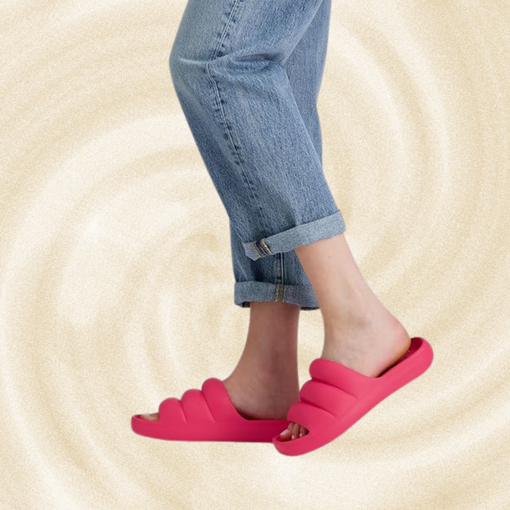 Person wearing rolled-up jeans and agleam  slides.