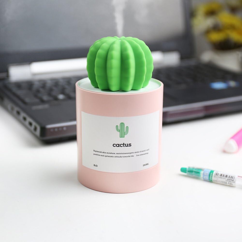 Cactus-shaped humidifier with a pinkish base, placed connected a table beside a laptop and a highlighter