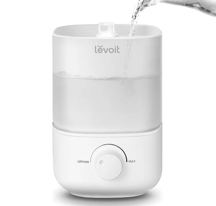 Compact Levoit humidifier with h2o  being poured in, featuring an adjustable dial for mist control