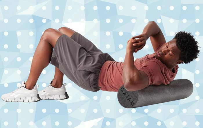 Person lying connected  a foam roller for backmost  stretching, wearing diversion  shorts, a casual t-shirt, and sneakers. Background features geometric shapes