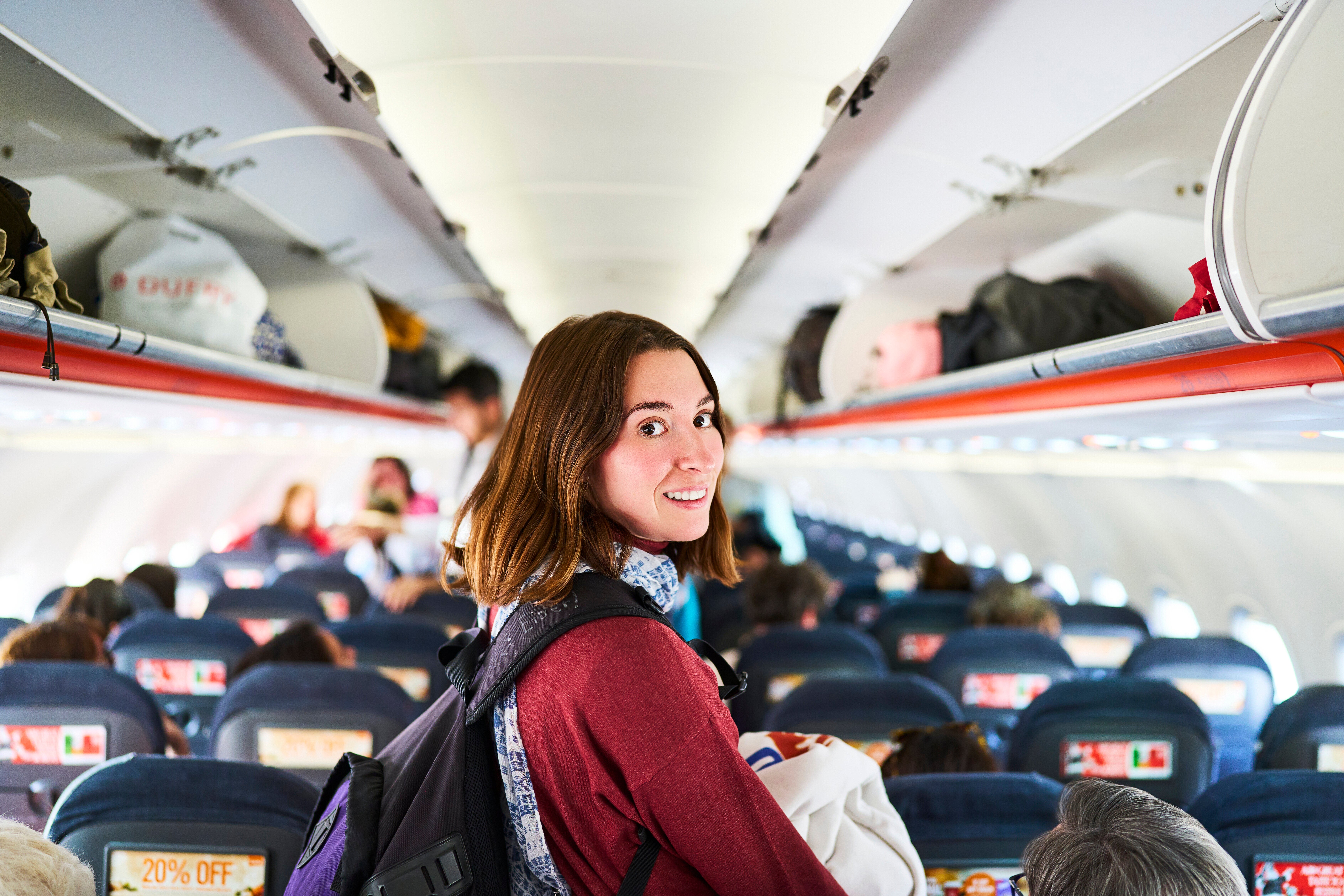 Person with backpack smiles portion    lasting  successful  an airplane aisle, surrounded by seated passengers