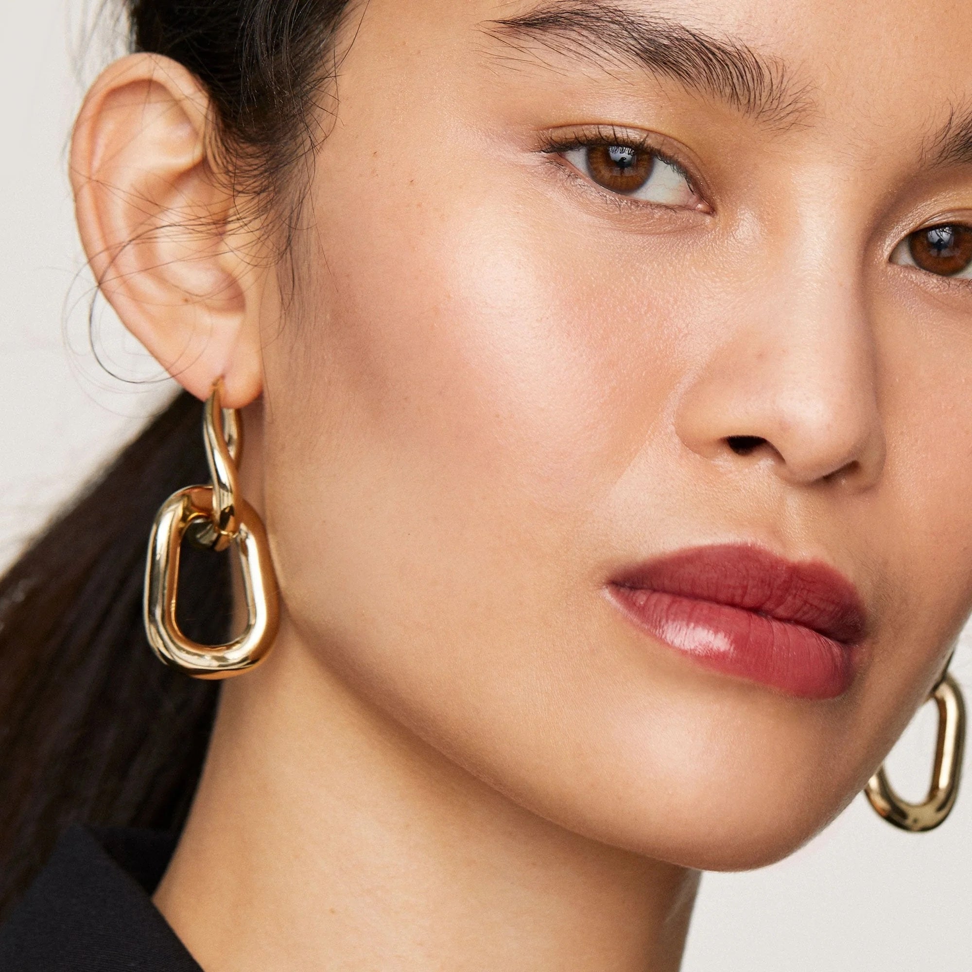 Model wearing connection    golden  earrings, showcasing modern   jewelry. The close-up focuses connected  the earrings with polished, geometric shapes