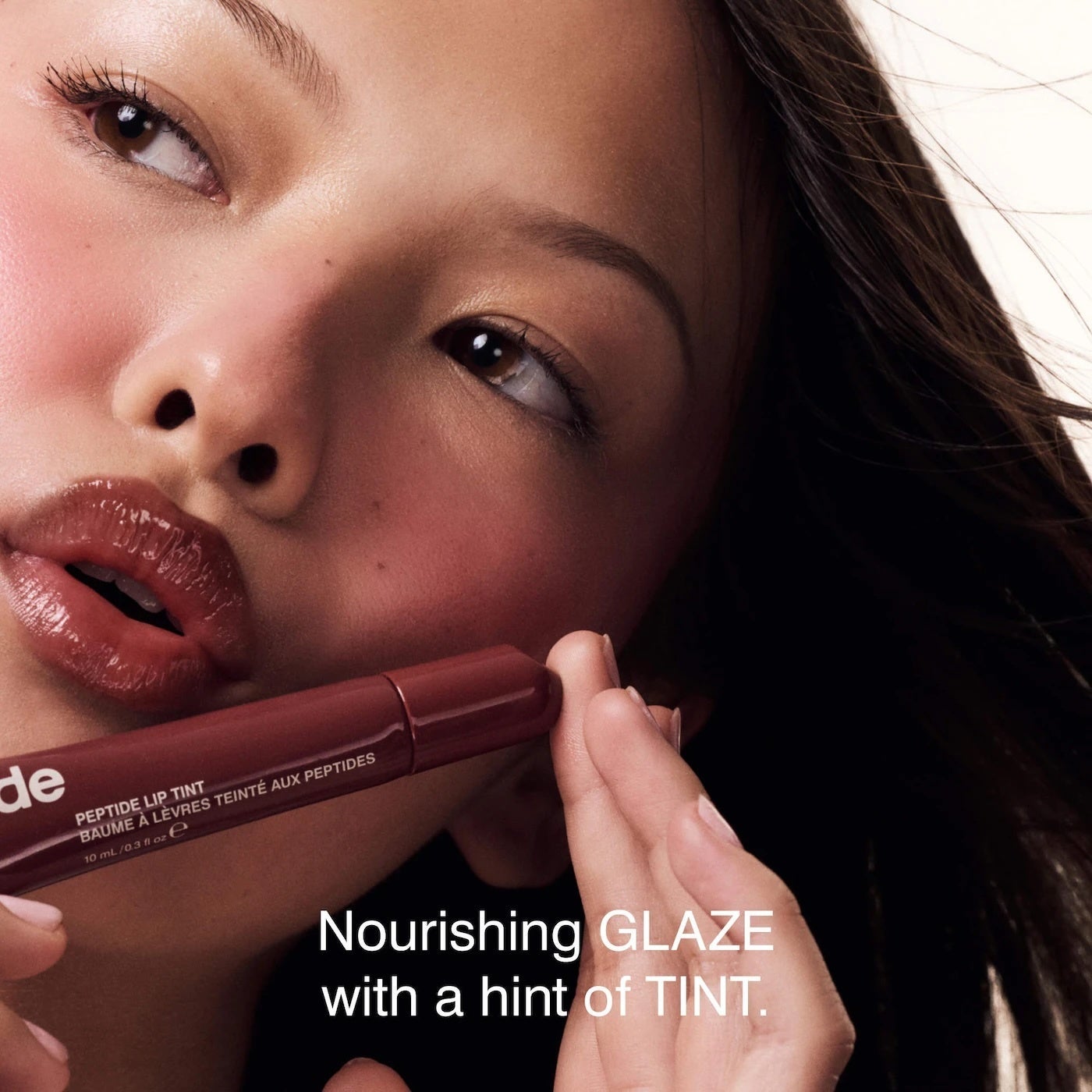 Close-up of a idiosyncratic   applying a glossy articulator  tint with the substance   "Nourishing GLAZE with a hint of TINT."