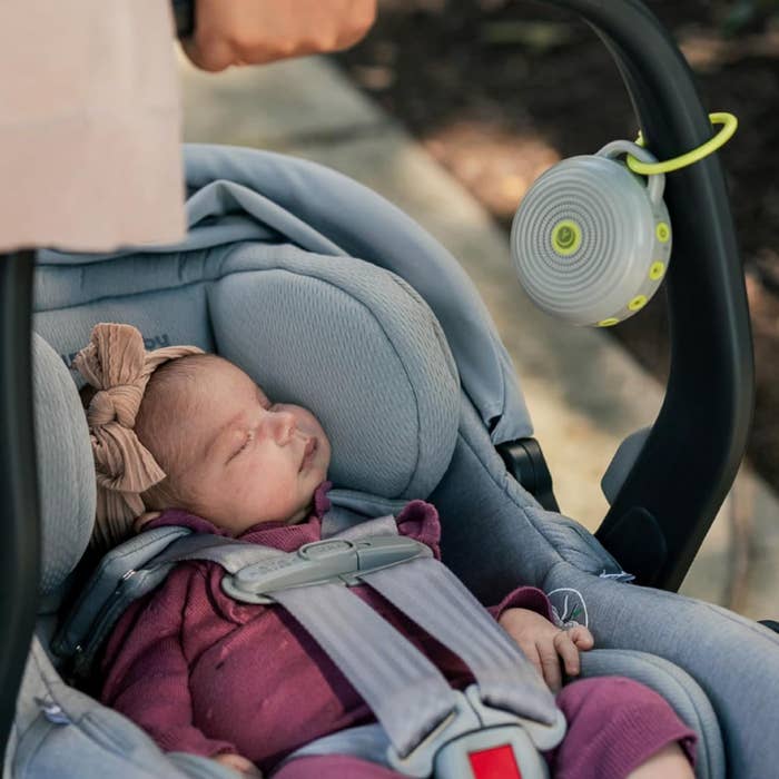 Baby sleeping successful  a car   spot   with a portable achromatic  sound  instrumentality   attached to the handle, illustrating a convenient question   accessory for parents