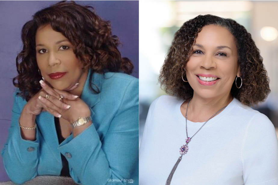 Two women smiling in professional attire. One is seated with hands clasped, wearing a blazer; the other stands, wearing a necklace and hoop earrings