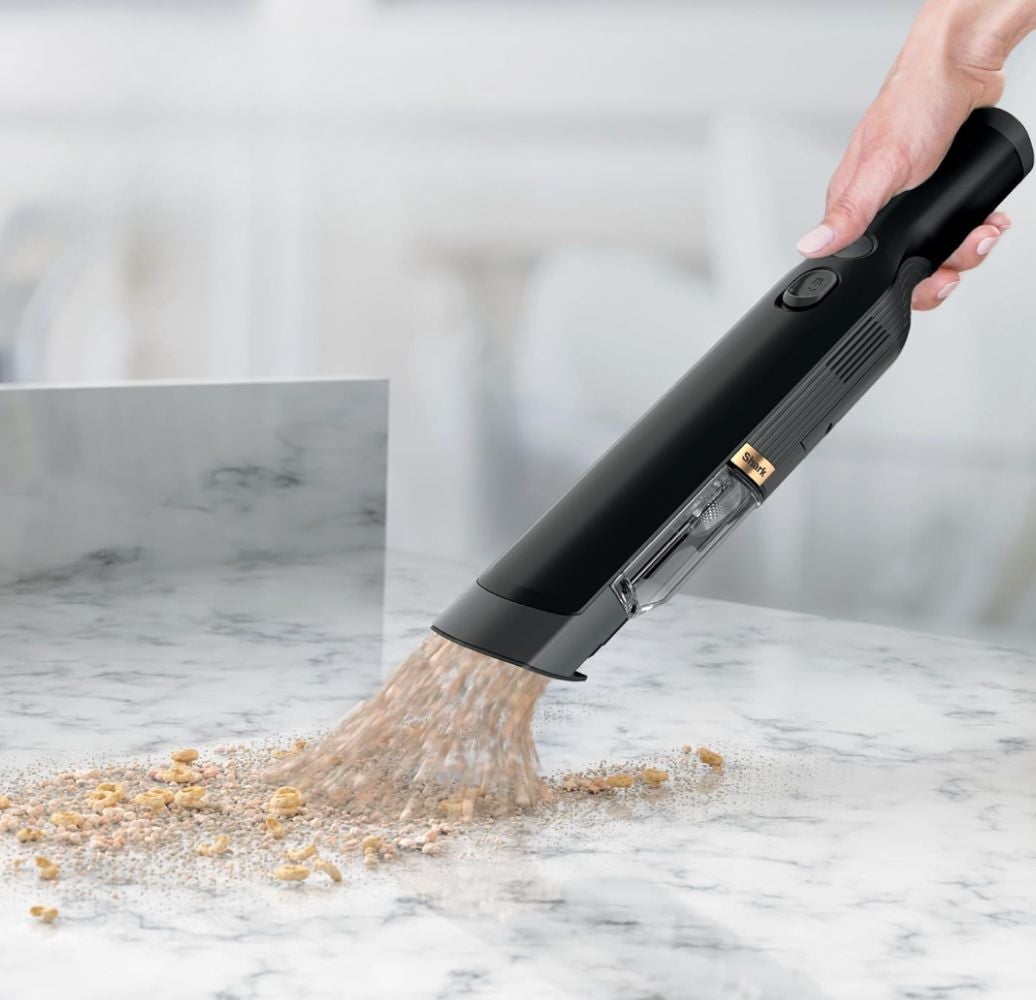 Handheld vacuum cleaner sucking up crumbs from a marble surface, illustrating its efficiency for quick cleanups in a shopping context