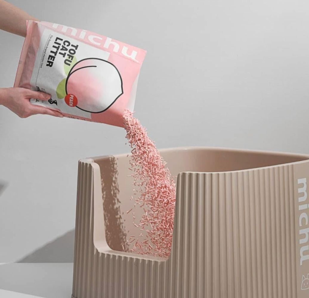 Person pouring tofu cat litter into a stylish modern cat litter box