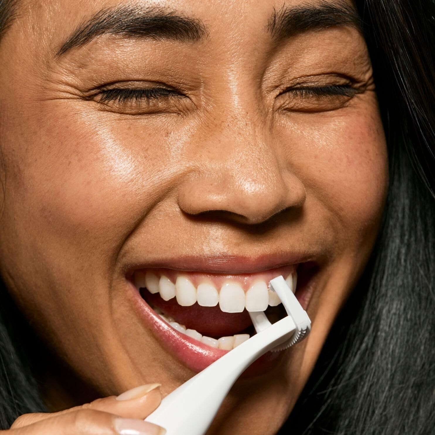 Person smiling portion utilizing an interdental brushwood betwixt teeth, demonstrating oral care
