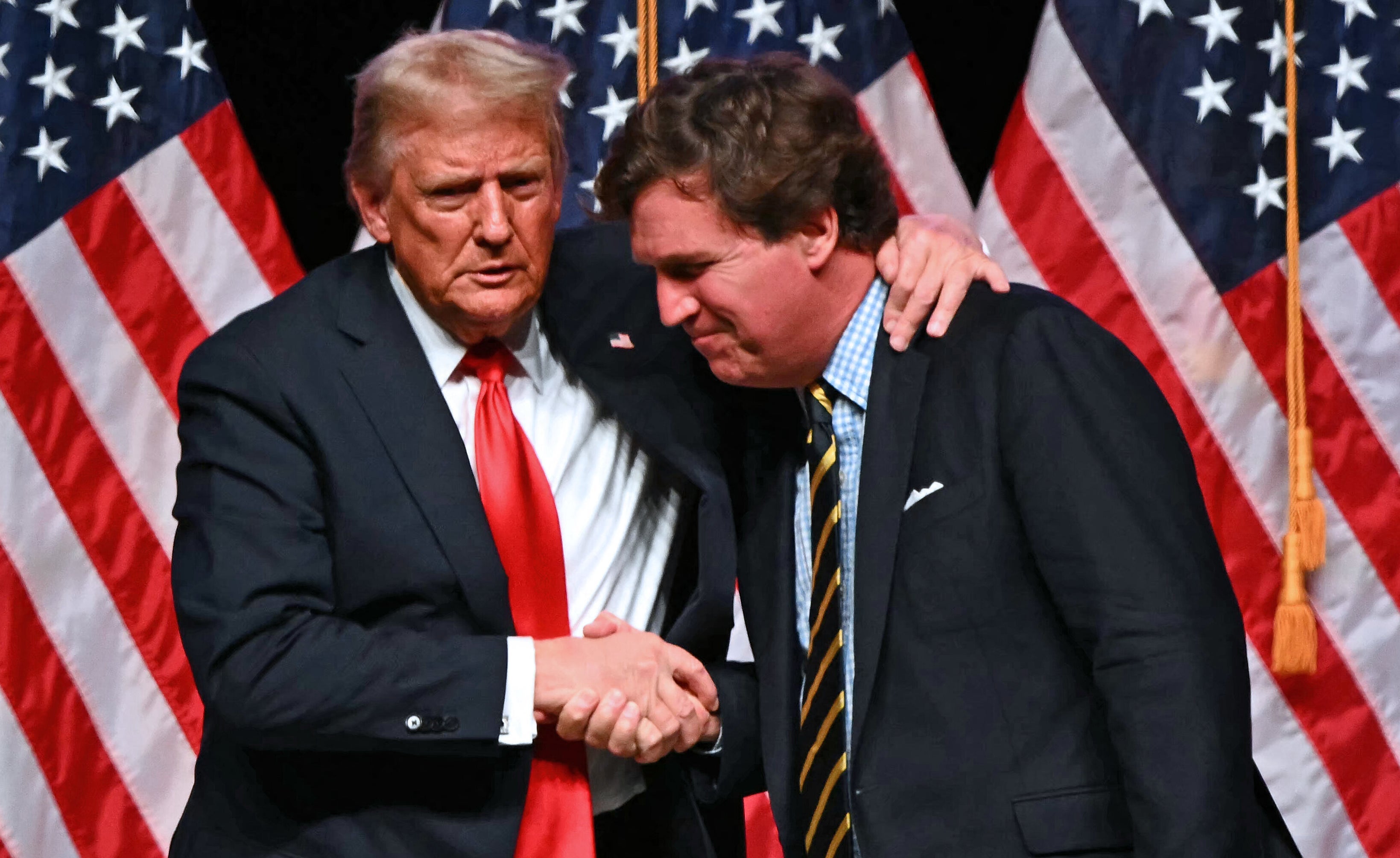 Two individuals successful  suits and ties are shaking hands connected  signifier    with aggregate  flags successful  the background