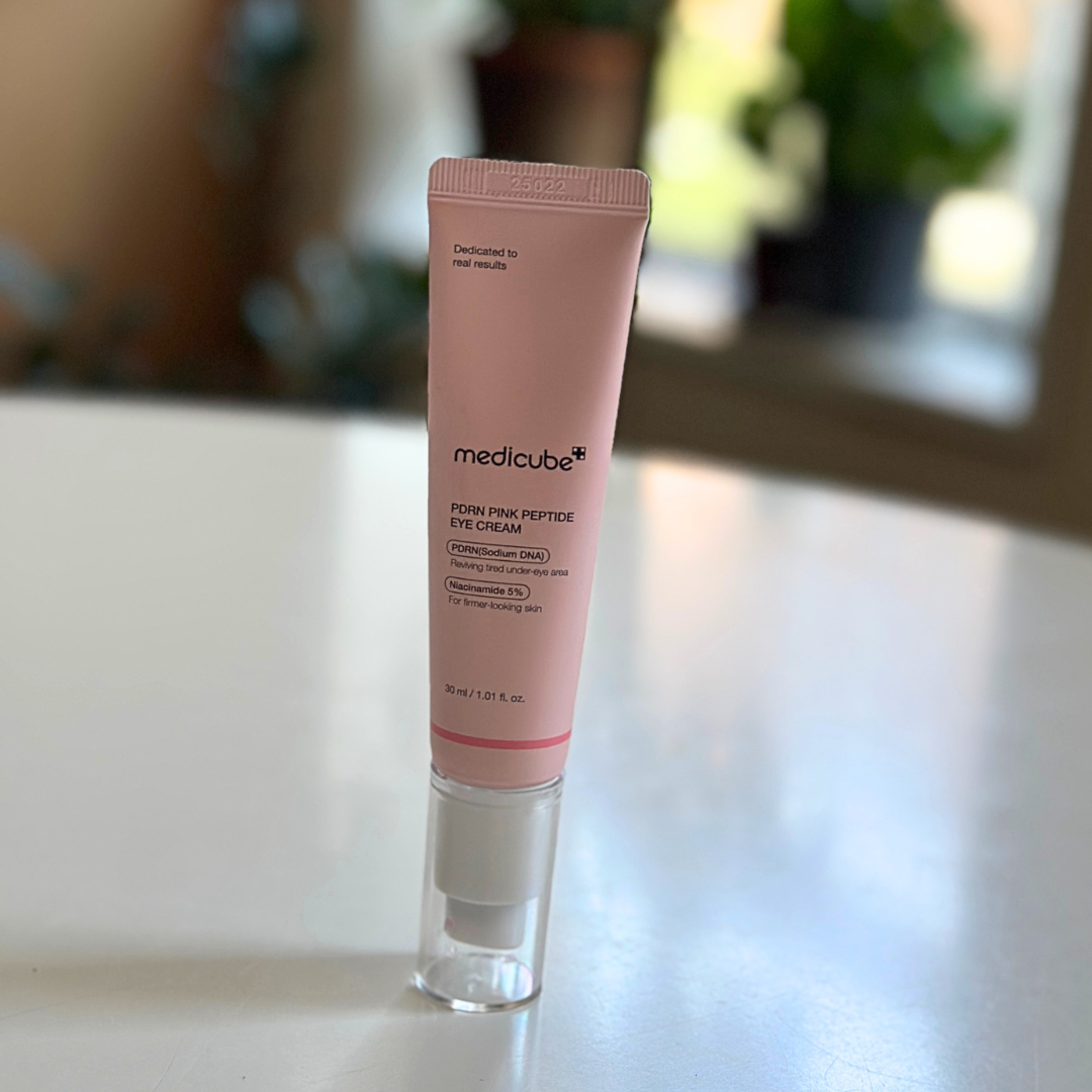 A vessel  of Medicube Porey Pink Peptide Eye Cream is placed connected  a array  with a blurred background