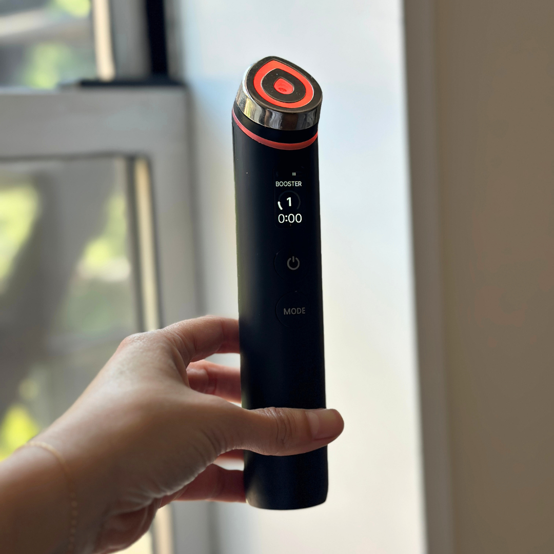 Hand holding a handheld physics  skincare device, displaying settings connected  a tiny  screen