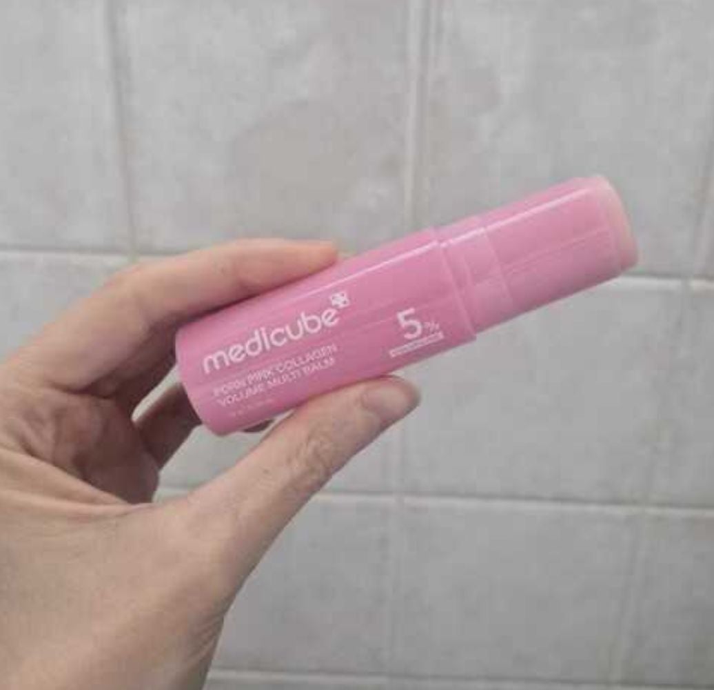 Hand holding a Medicube merchandise  conduit  labeled "5%" against a tiled background