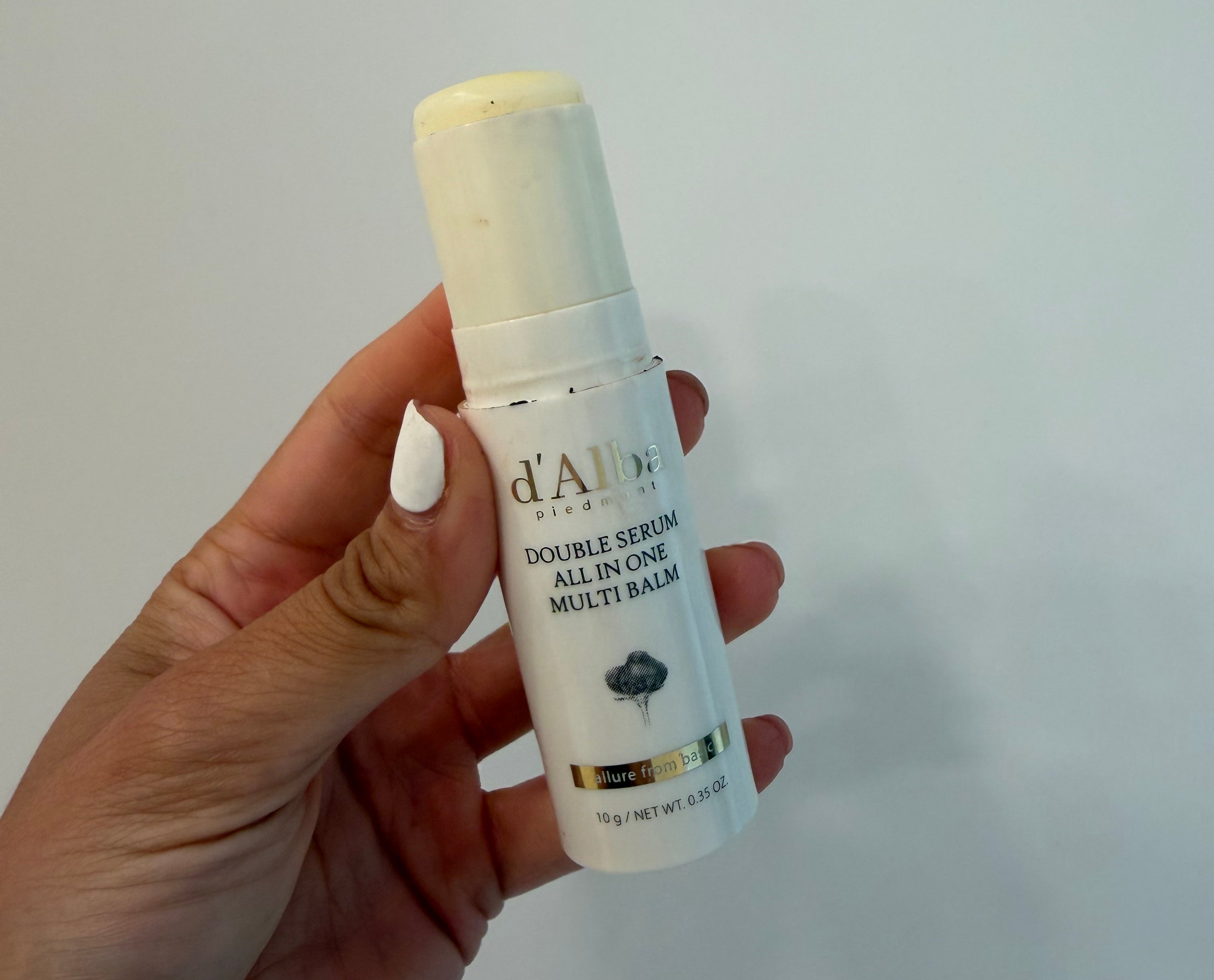 Hand holding a conduit  of d'Alba Double Serum All In One Multi Balm, suitable for skincare