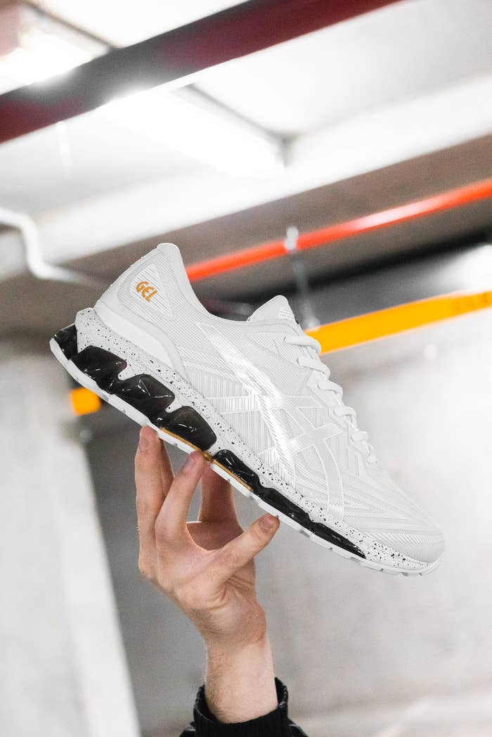 Photo of a white ASICS Gel Quantum 360 VII, with a black and white midsole held in a hand.