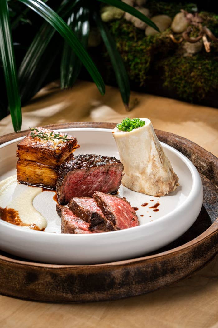 A plate with wagyu ribeye steak, bone marrow, and a crispy potato