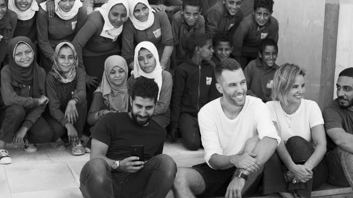 Kotn co-founders sitting with schoolchildren in rural Egypt after helping fund a new school via ABCs Project.