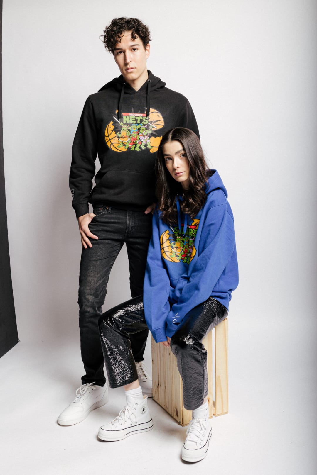 Two models wearing Peace Collective x NBA hoodies