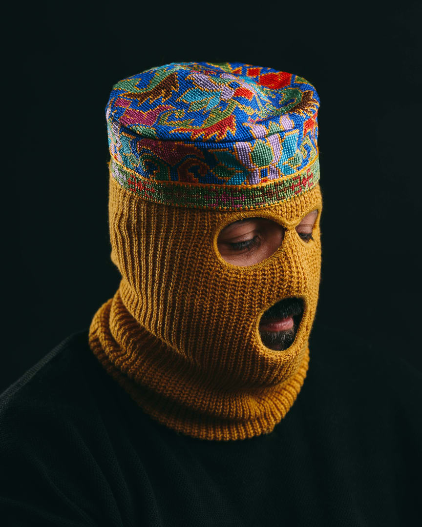Rapper Narcy wearking a yellow balaclava and a colourful hat.