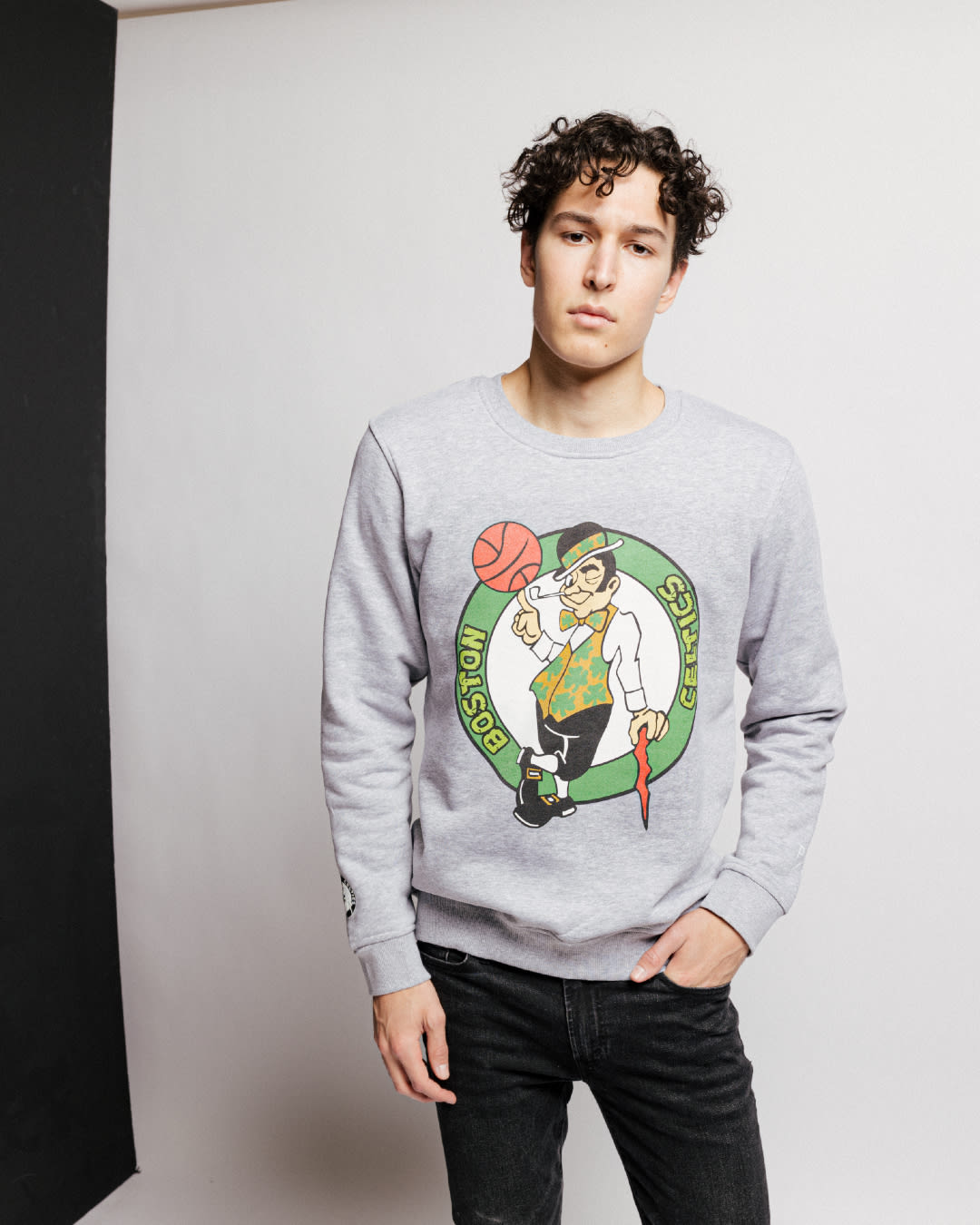 Model wearing a grey crewneck with the Boston Celtics logo in green tmnt font