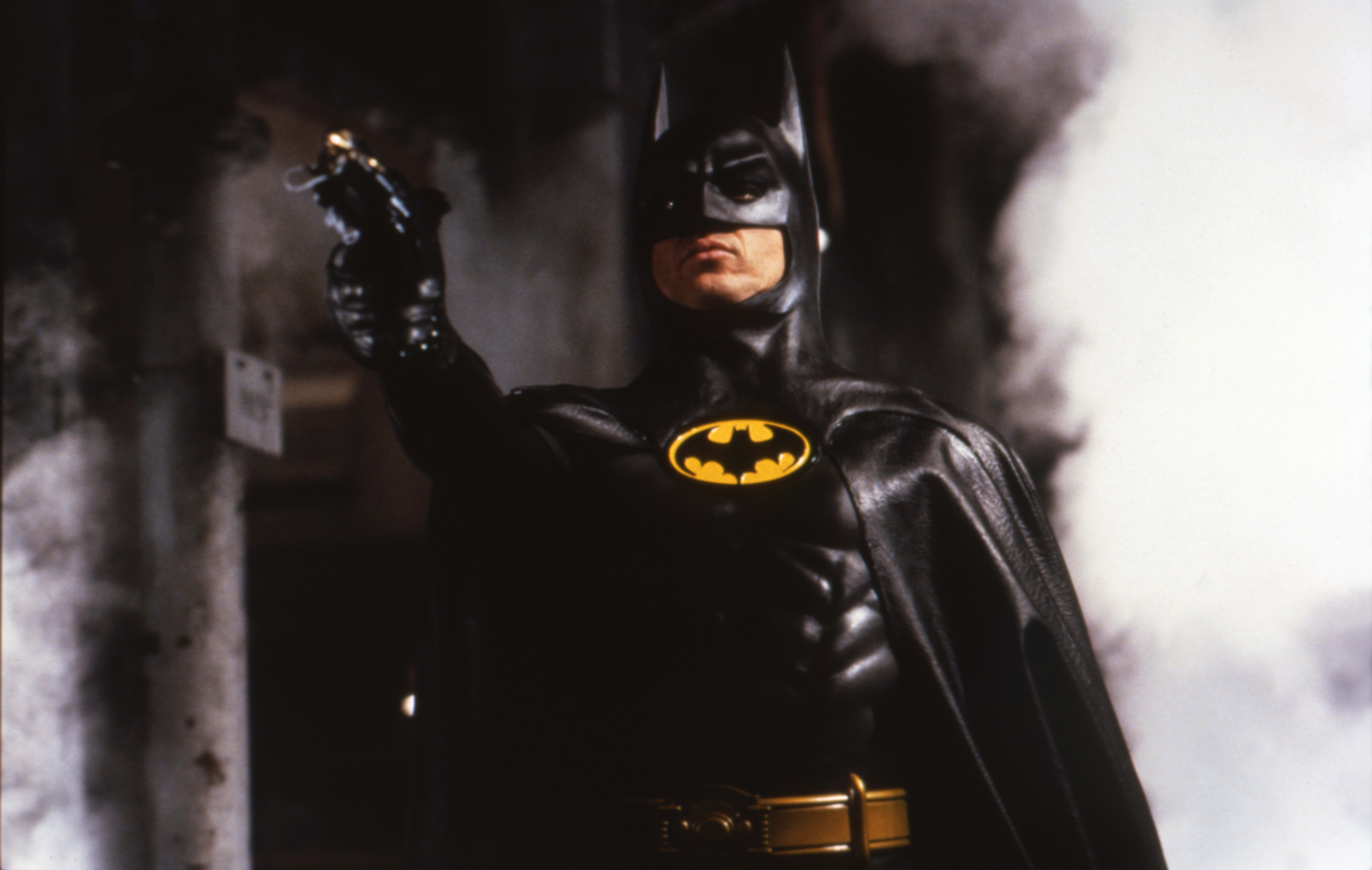 Michael Keaton as Batman pointing a gun
