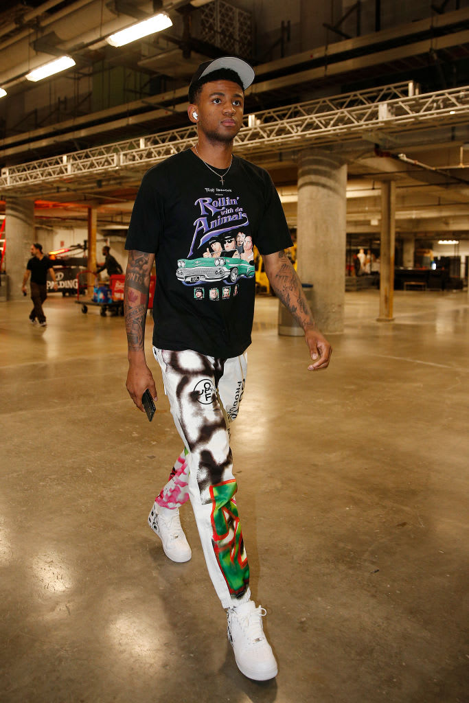 Nickeil Alexander-Walker wearing white pants with a graffiti design and a graphic tee