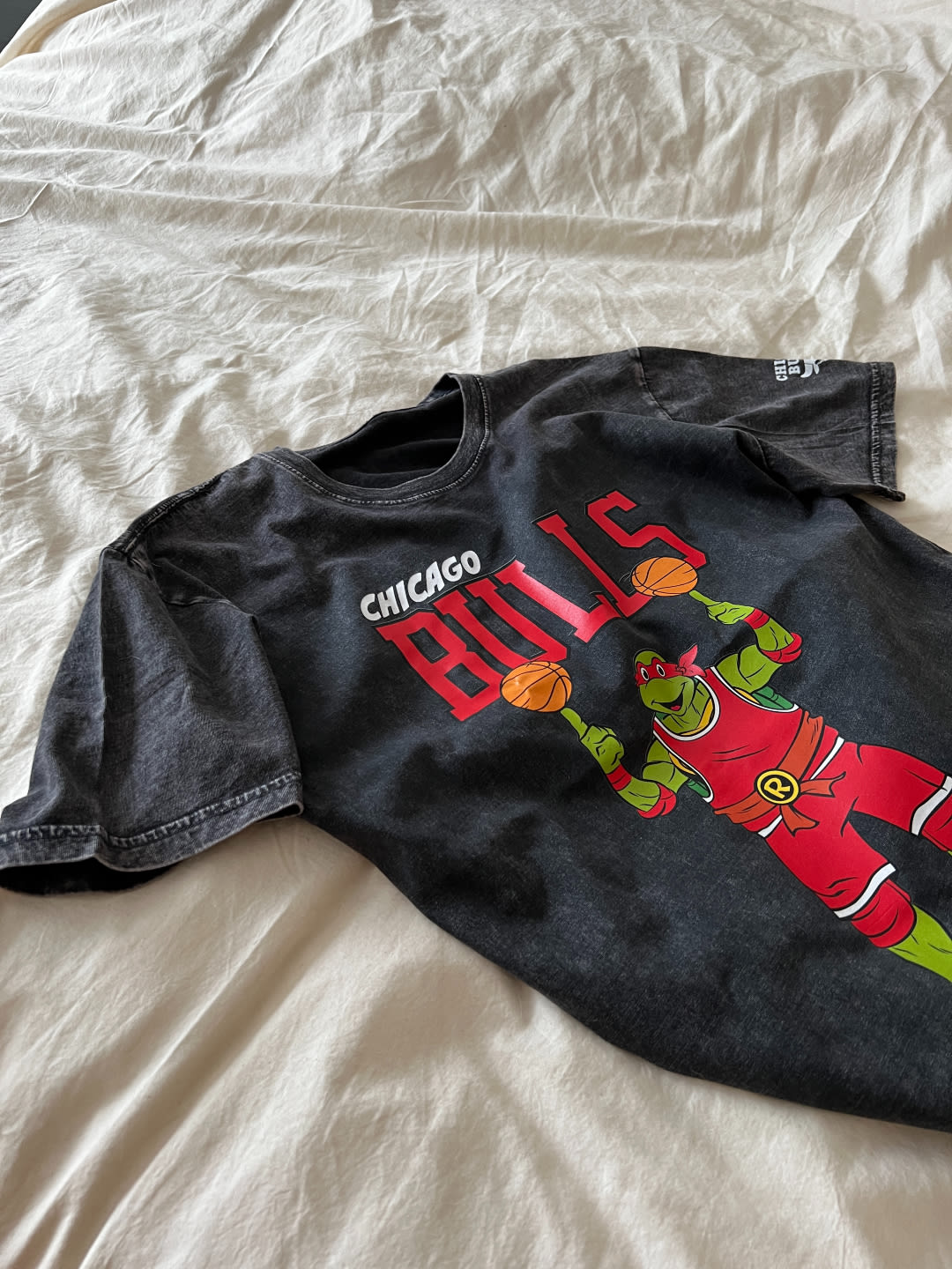 A Chicago Bulls TMNT x NBA shirt resting on a sheet.