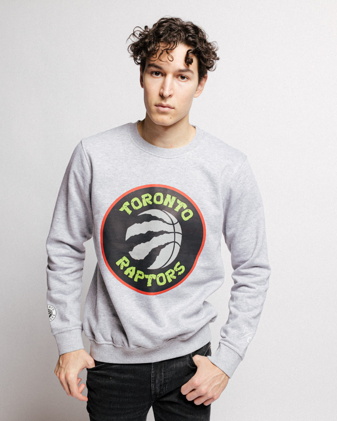 A model wearing a grey turtleneck with the Raptors logo with a green, TMNT font