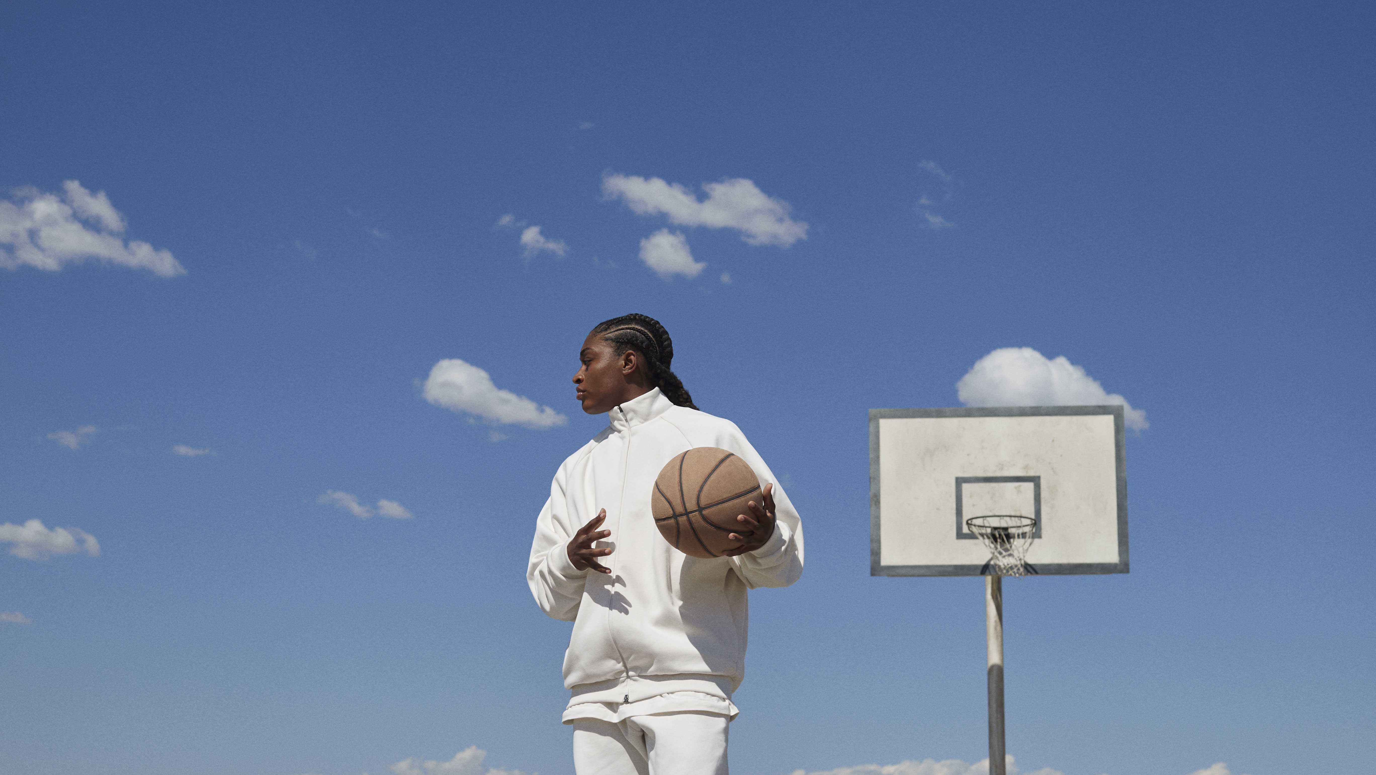 A girl in front of a basketball backboard holding a basketball