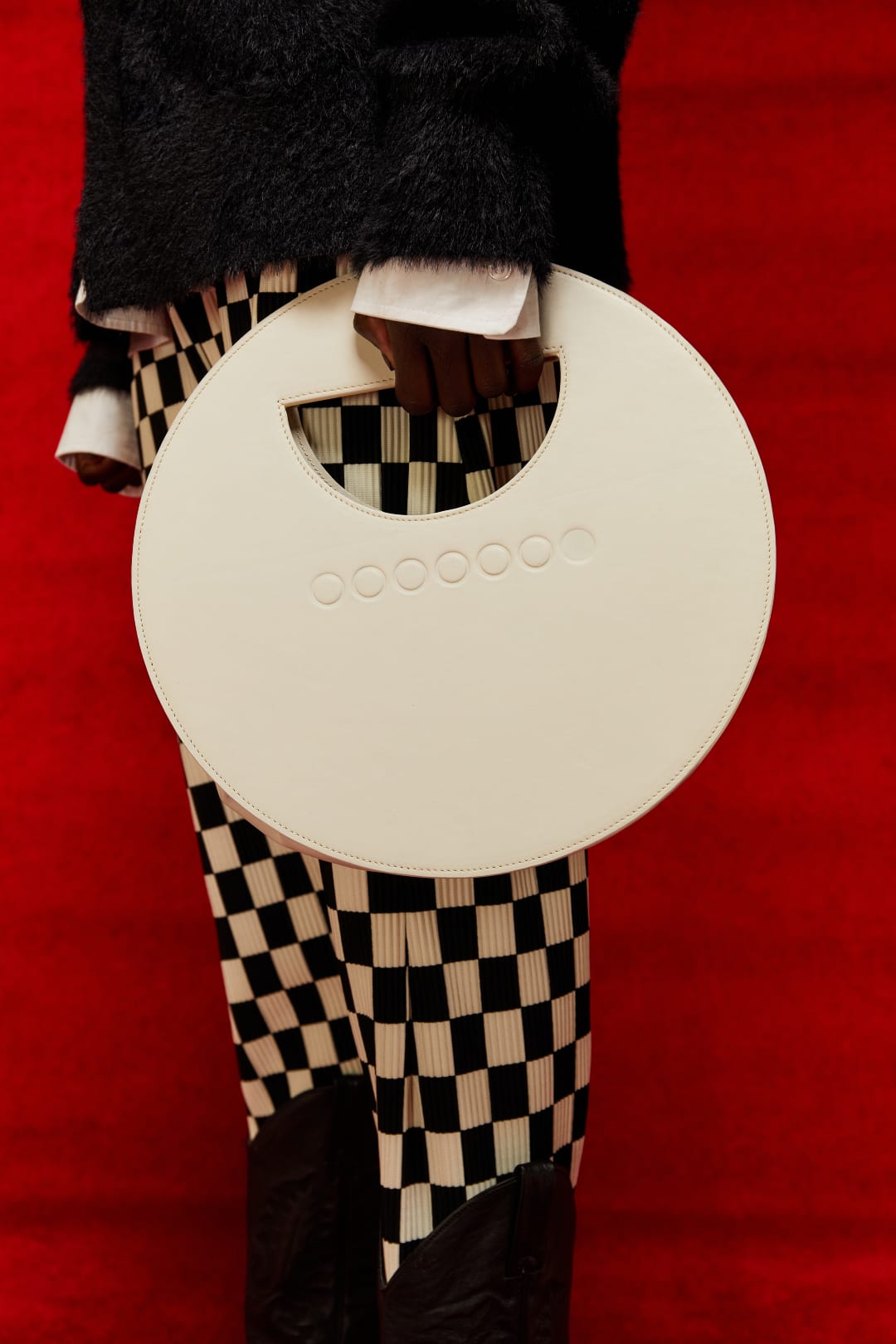 A model holding a white circle-shaped bag