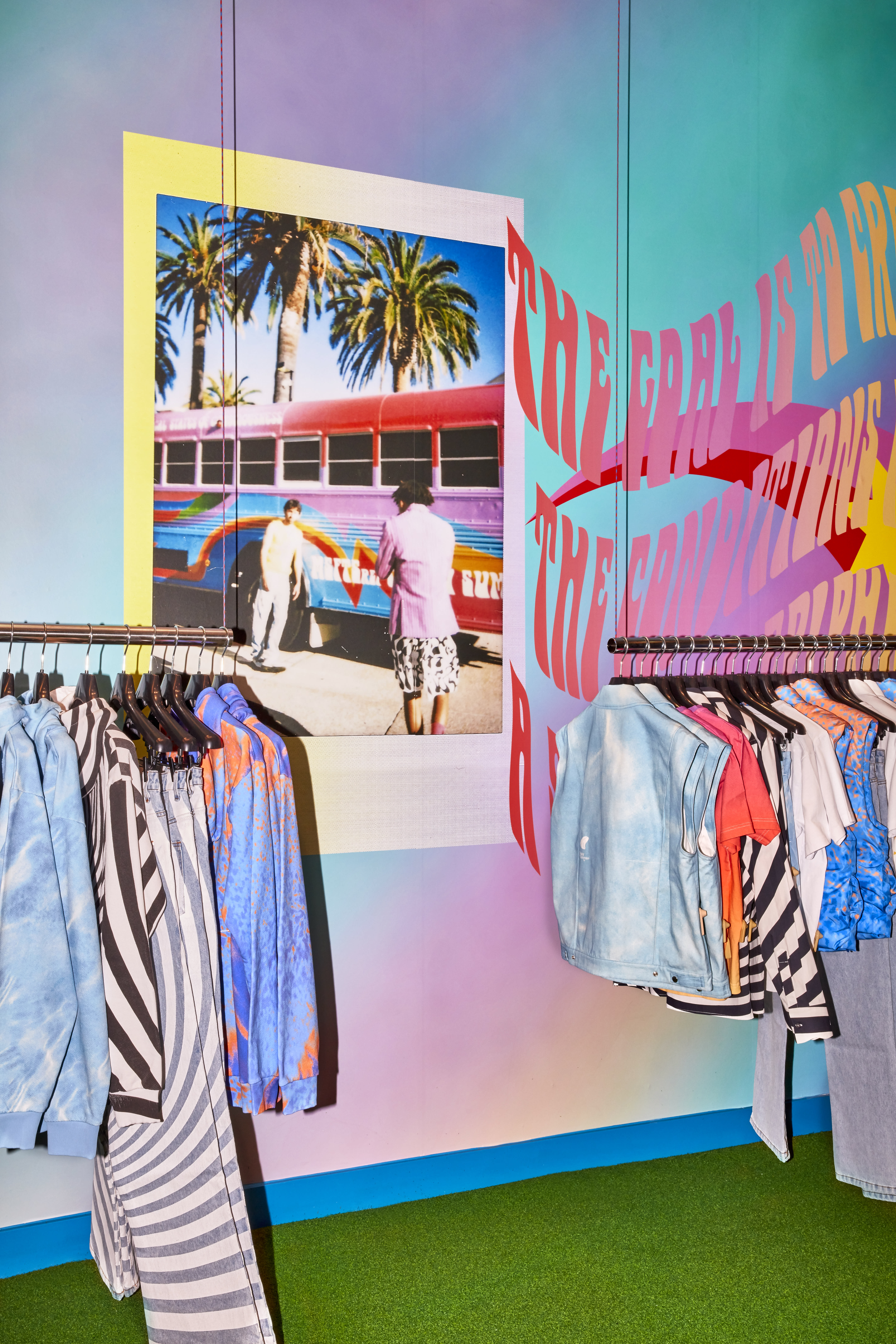 A rack of clothes in front of a colourful wall