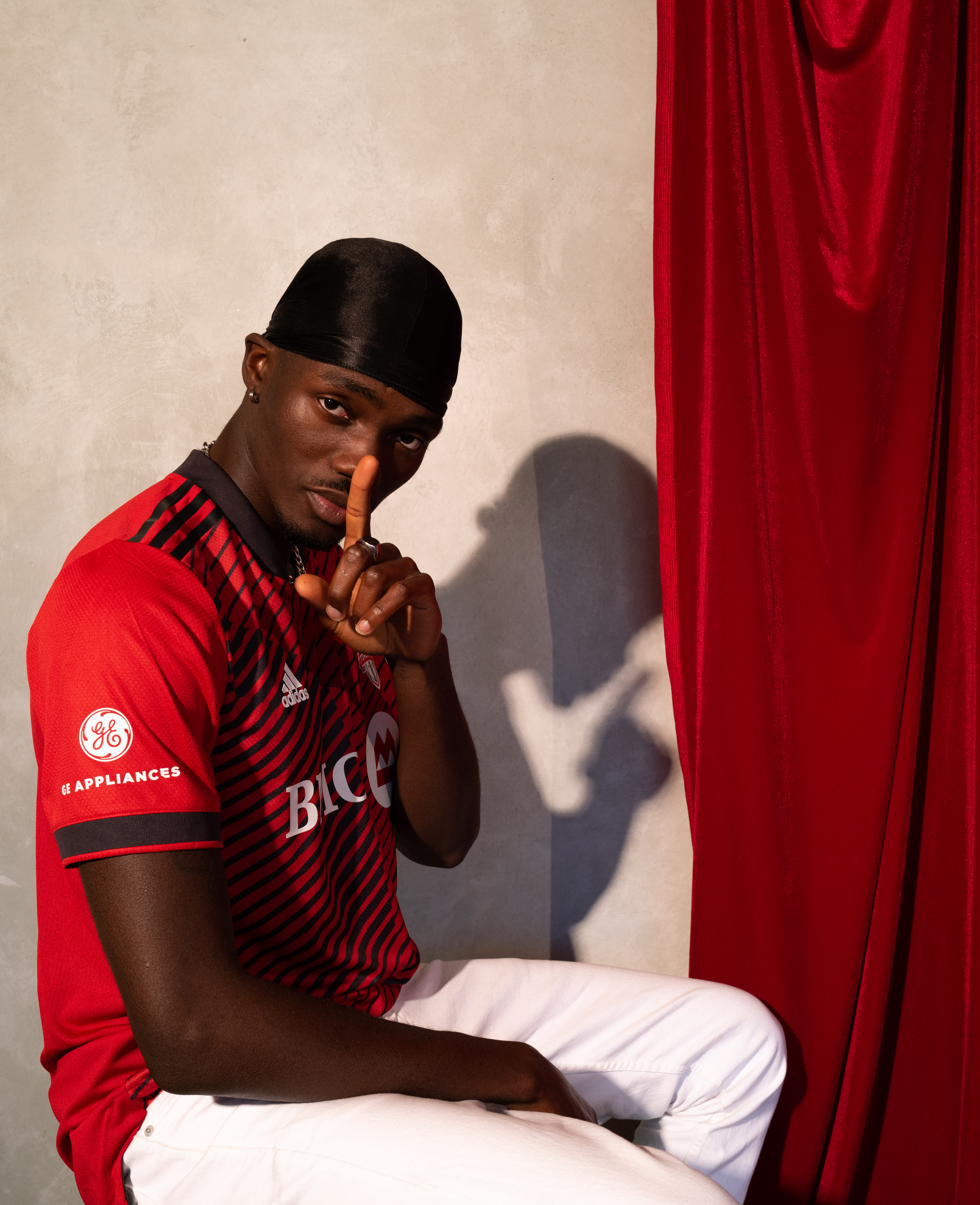 Tobi posting in a red Toronto FC jersey pointing