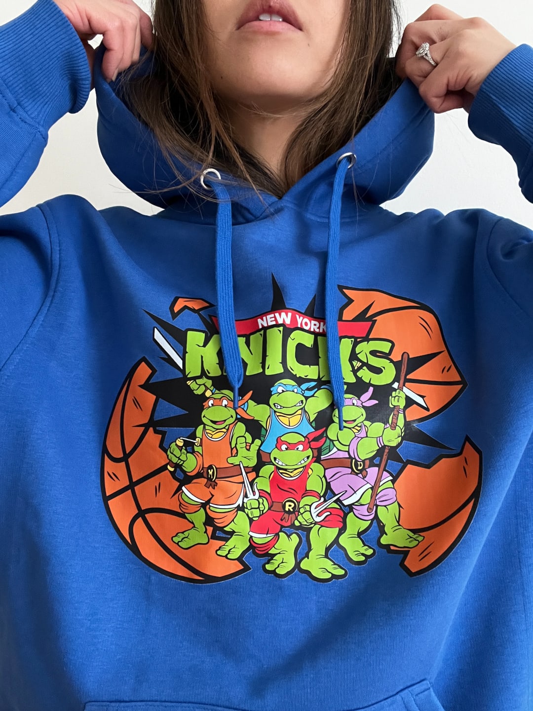 Model wearing a blue hoodie with the TMNT characters that read &#x27;New York Knicks&quot;